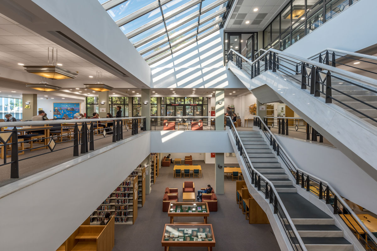 view of library interview with stairs on right and skylights, natural light bathing the space