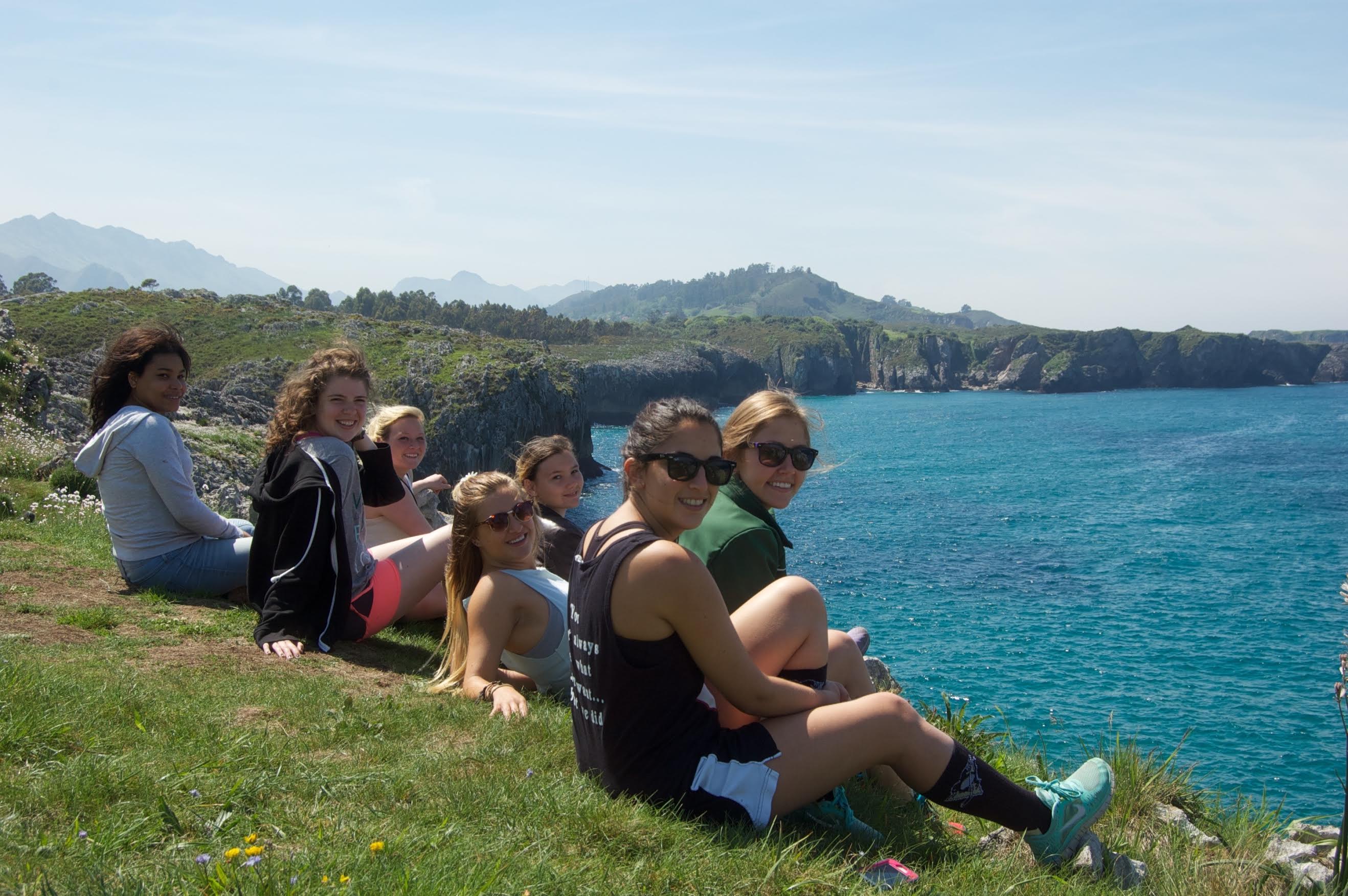 students sitting along the sea edge in Spain