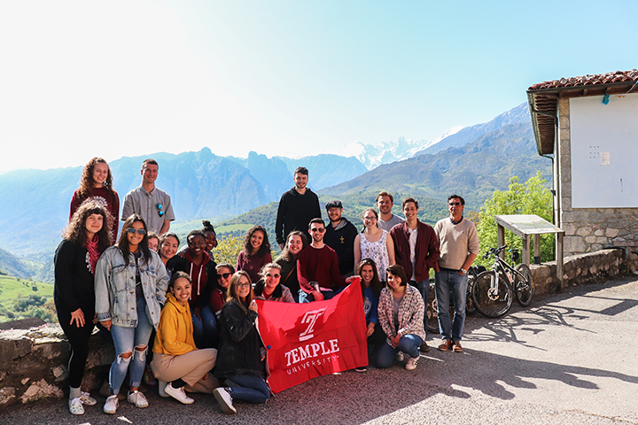 students holding Temple flag in Spain with moutains in the background-by Dylan Long