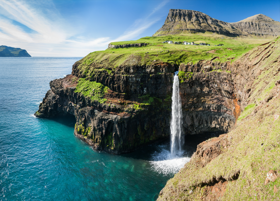 waterfall on faroe islands and the village Gasadalur in background